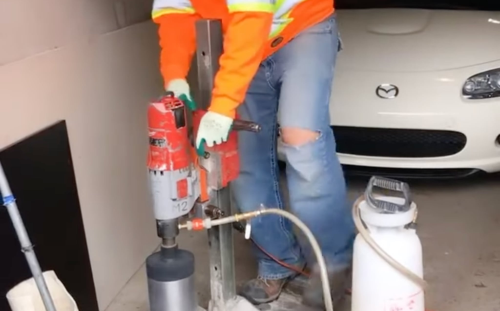 Image of a construction worker drilling into a basement slab for a pyrite test.