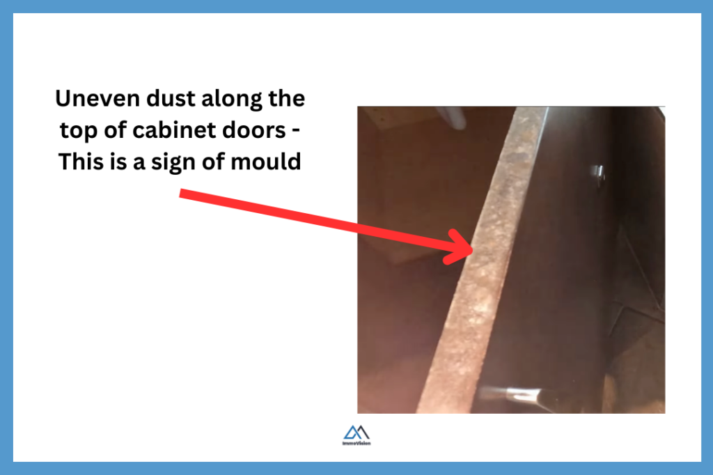 Uneven dust patterns on top of cabinet doors indicating possible hidden moisture and mould.
